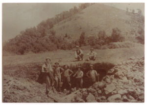 Archival sepiatone image of men in a hole digging for mastodon bones in Boaz, Wisconsin