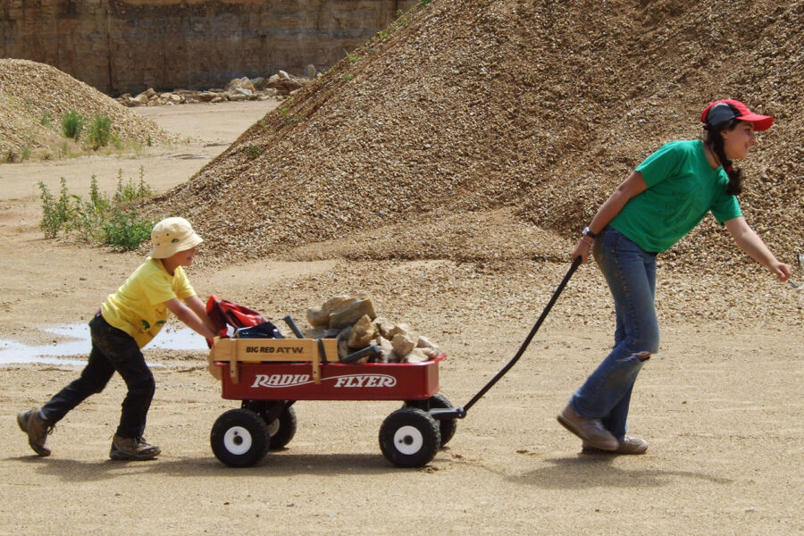 Two children pull a wagon of fossils